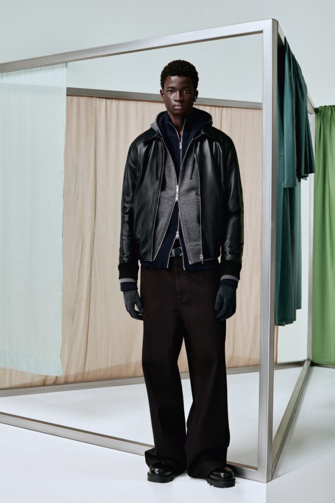 A relaxed black leather jacket paired with wide-leg gray cotton pants.