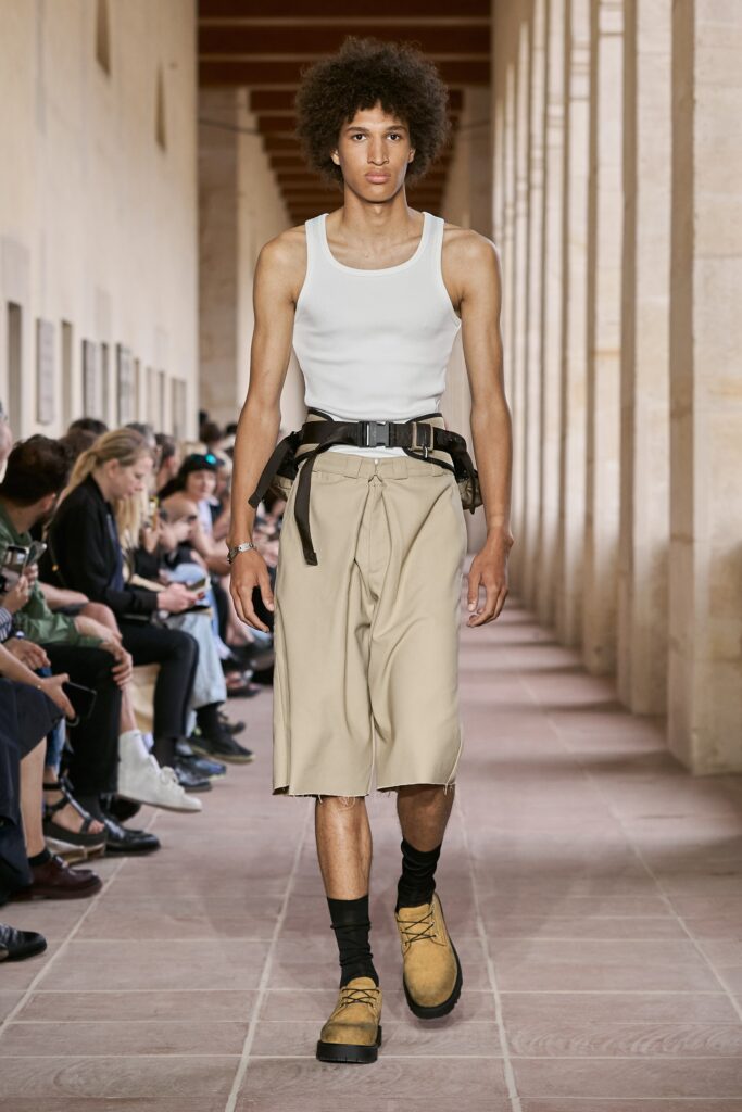 A fitted white sleeveless tank-top paired with high-waisted beige shorts featuring a straight-leg design.