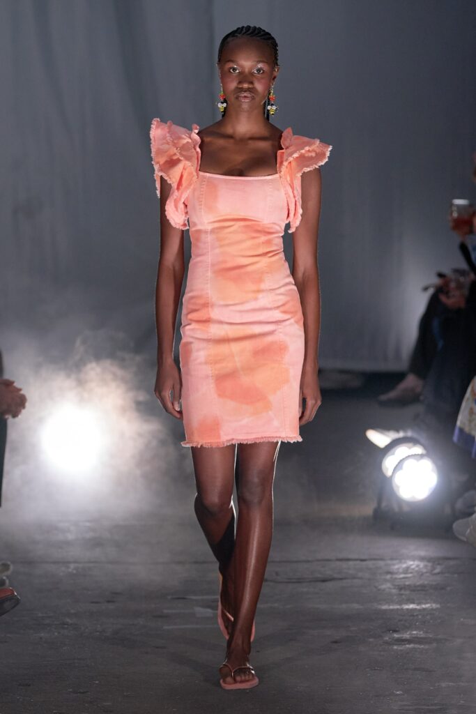 A fitted pink sleeveless dress with ruffled details and a high-waisted design.