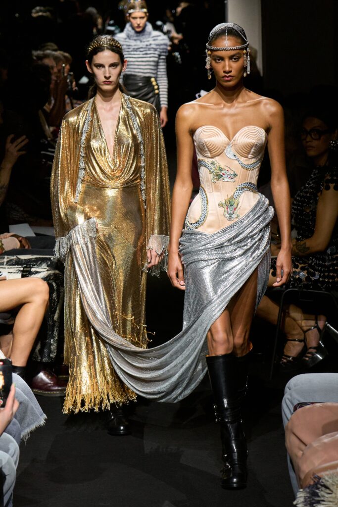 A fitted silver silk dress with a V-neckline and asymmetric design detail.