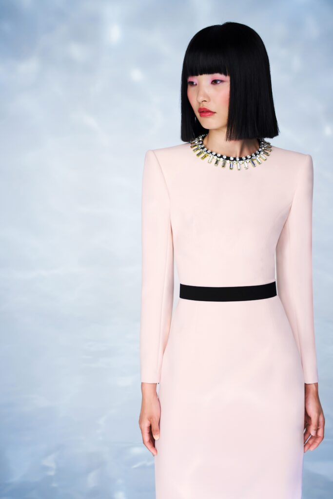 A fitted pink silk dress with long sleeves and a high neckline, featuring a straight-leg silhouette.