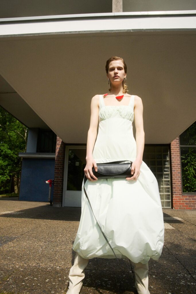 A relaxed green cotton sleeveless dress with a high neckline and tiered design.