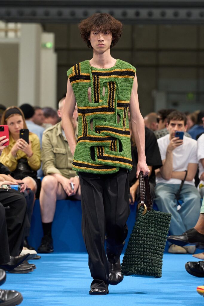 A relaxed green cotton sleeveless top with an asymmetric design paired with black pants.