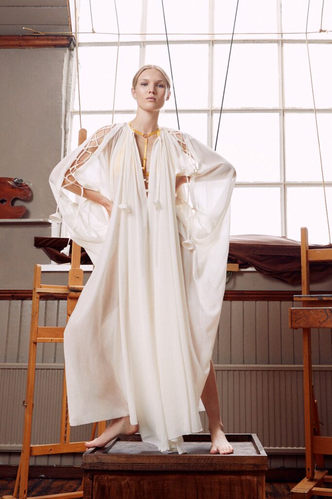 A relaxed white silk dress with a high neckline and layered design details.