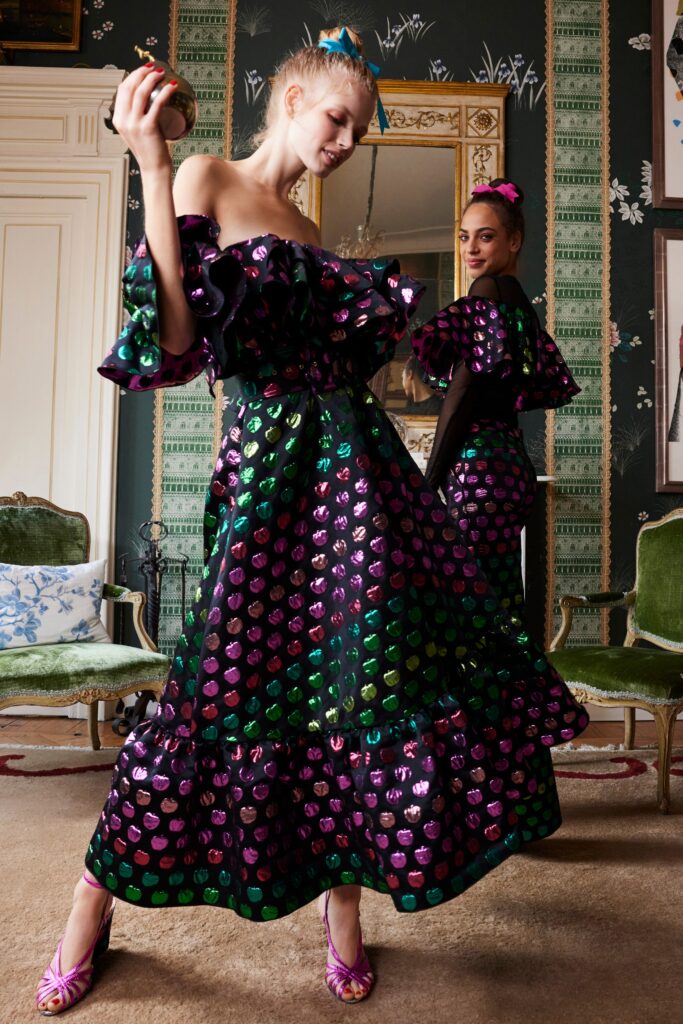 A fitted off-shoulder dress with ruffled sleeves and a printed design in black, green, and purple.