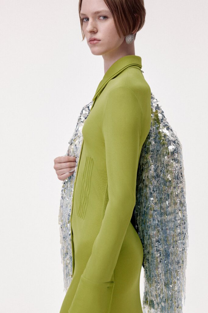 A fitted green silk dress with long sleeves, a collared neckline, and an asymmetric design.