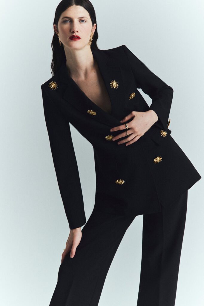 A tailored black blazer with a V-neckline and matching pants, featuring button details.