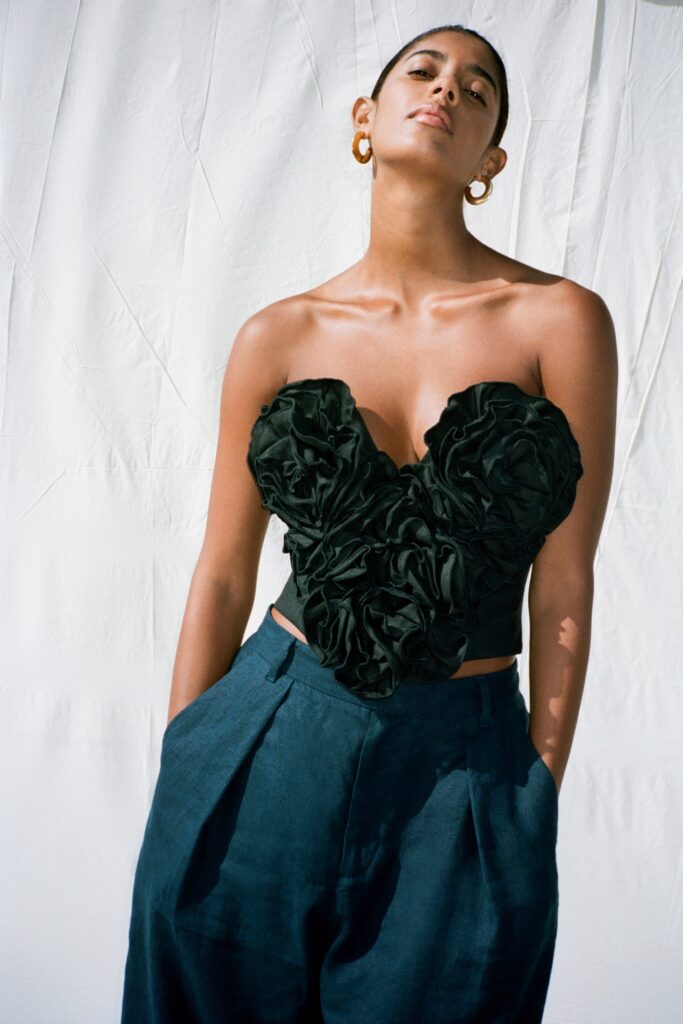 A fitted black ruffled sleeveless top paired with high-waisted blue wide-leg pants.