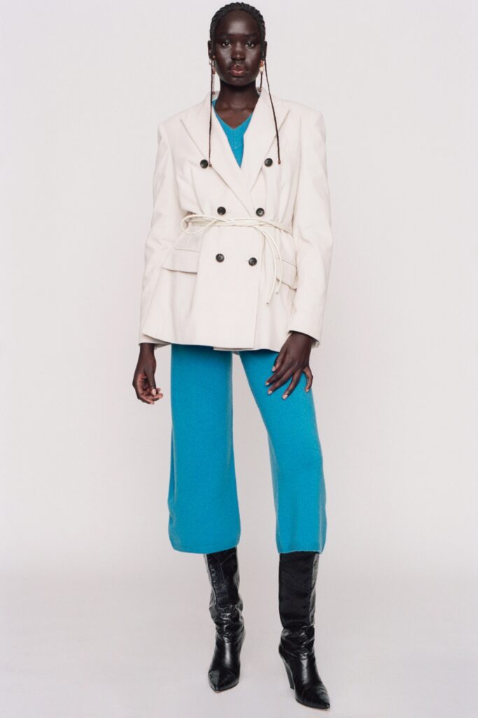 A fitted white jacket paired with blue pants featuring a V-neckline and wide-leg design.