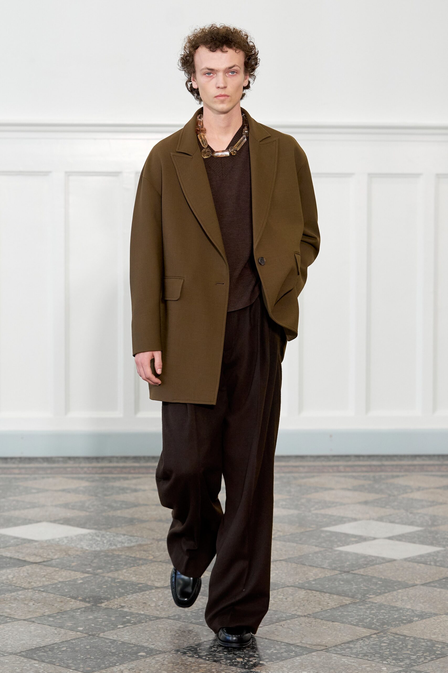 A relaxed brown jacket with long sleeves and a collared neckline paired with straight-leg pants.