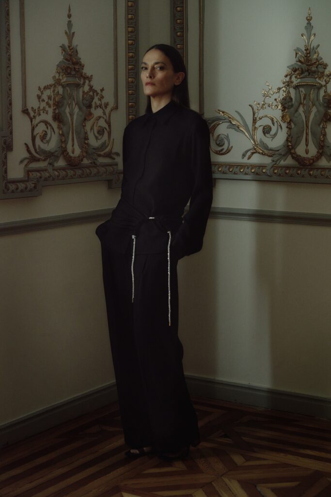 A relaxed black shirt with long sleeves and a collared neckline paired with straight-leg pants.