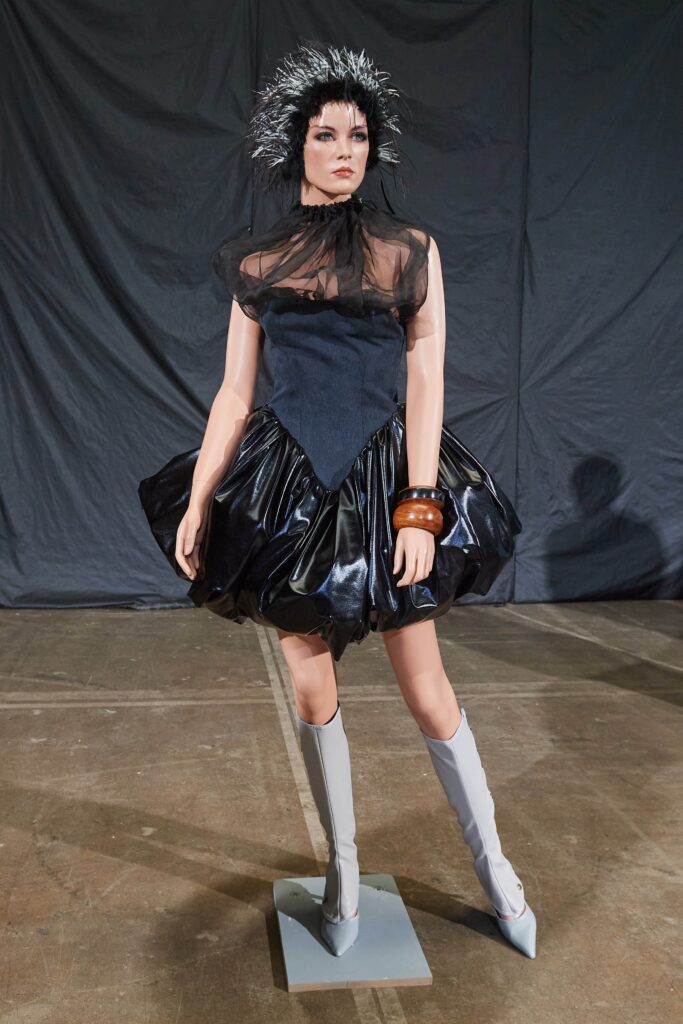 A fitted black silk sleeveless dress with a high neckline and layered design.