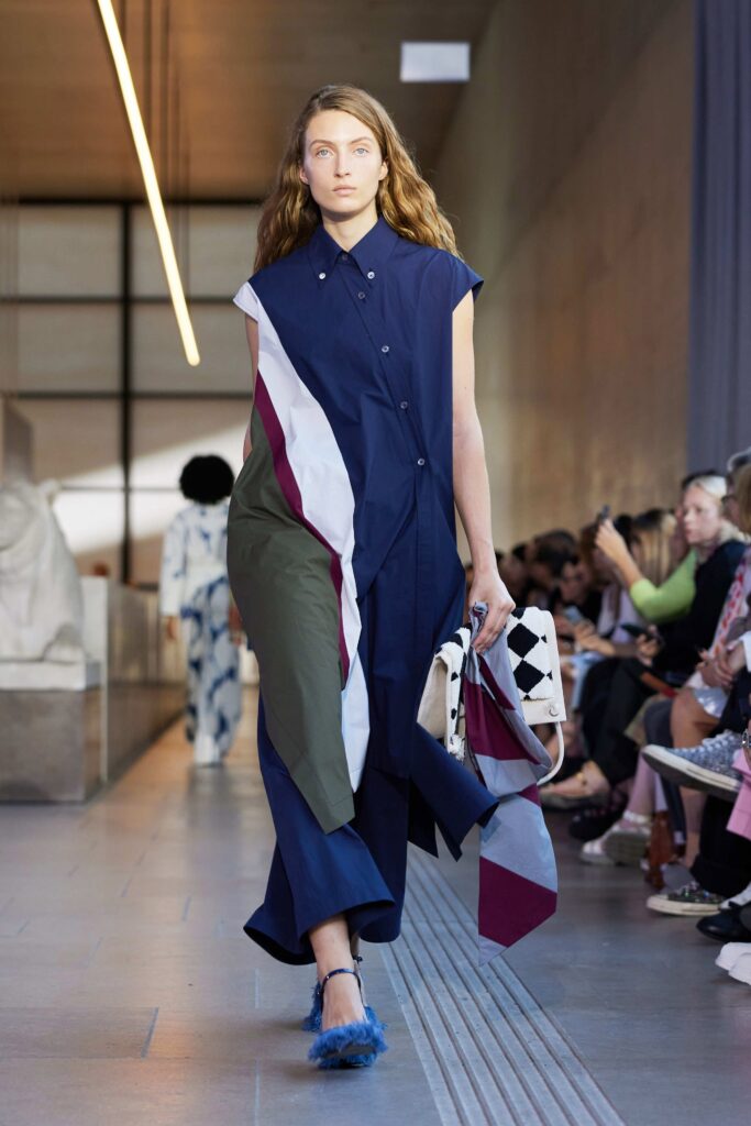 An asymmetric collared dress in blue, green, and red with a buttoned front.