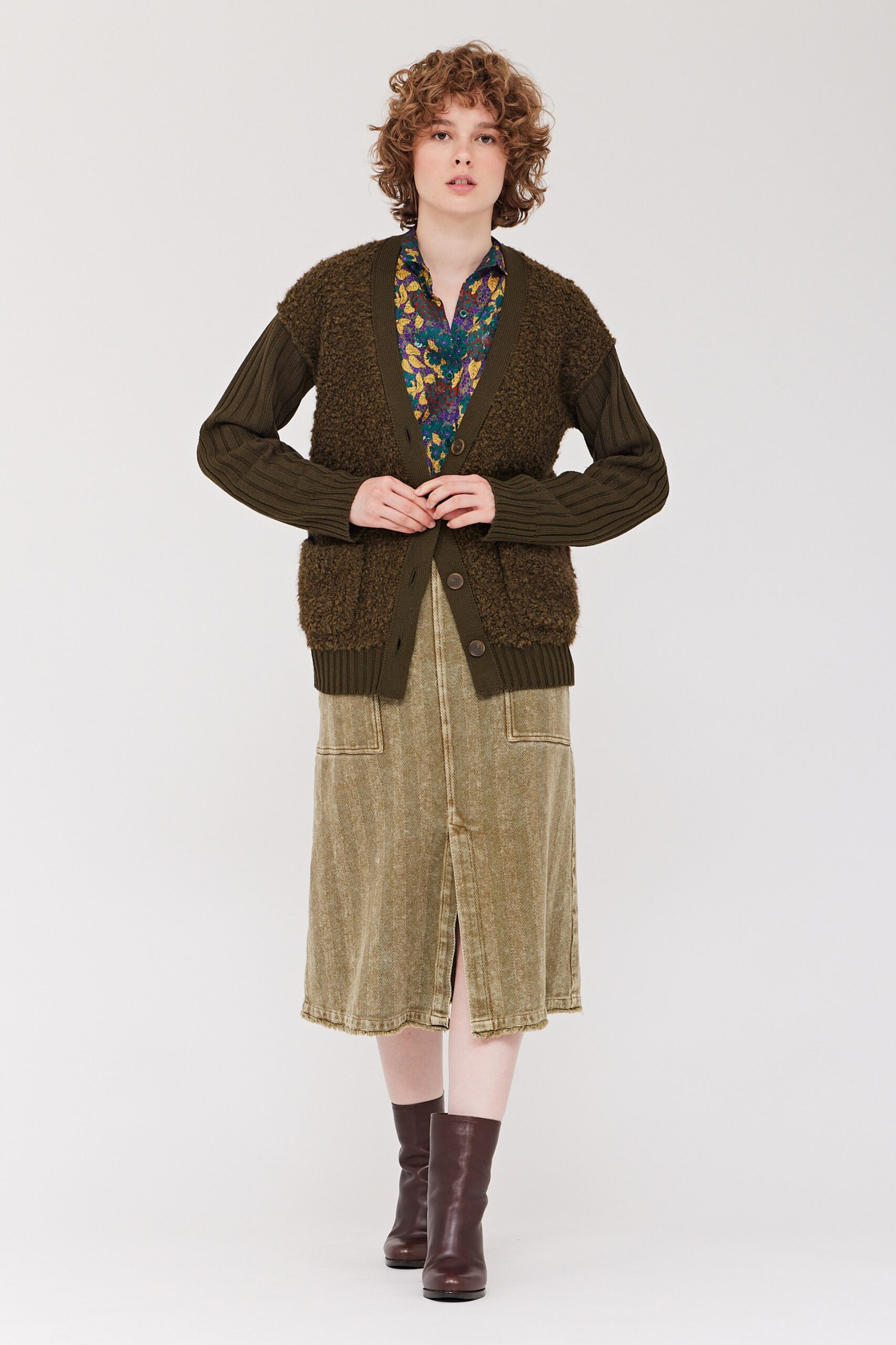 A relaxed green cardigan layered over a multicolor collared dress with a tiered design.