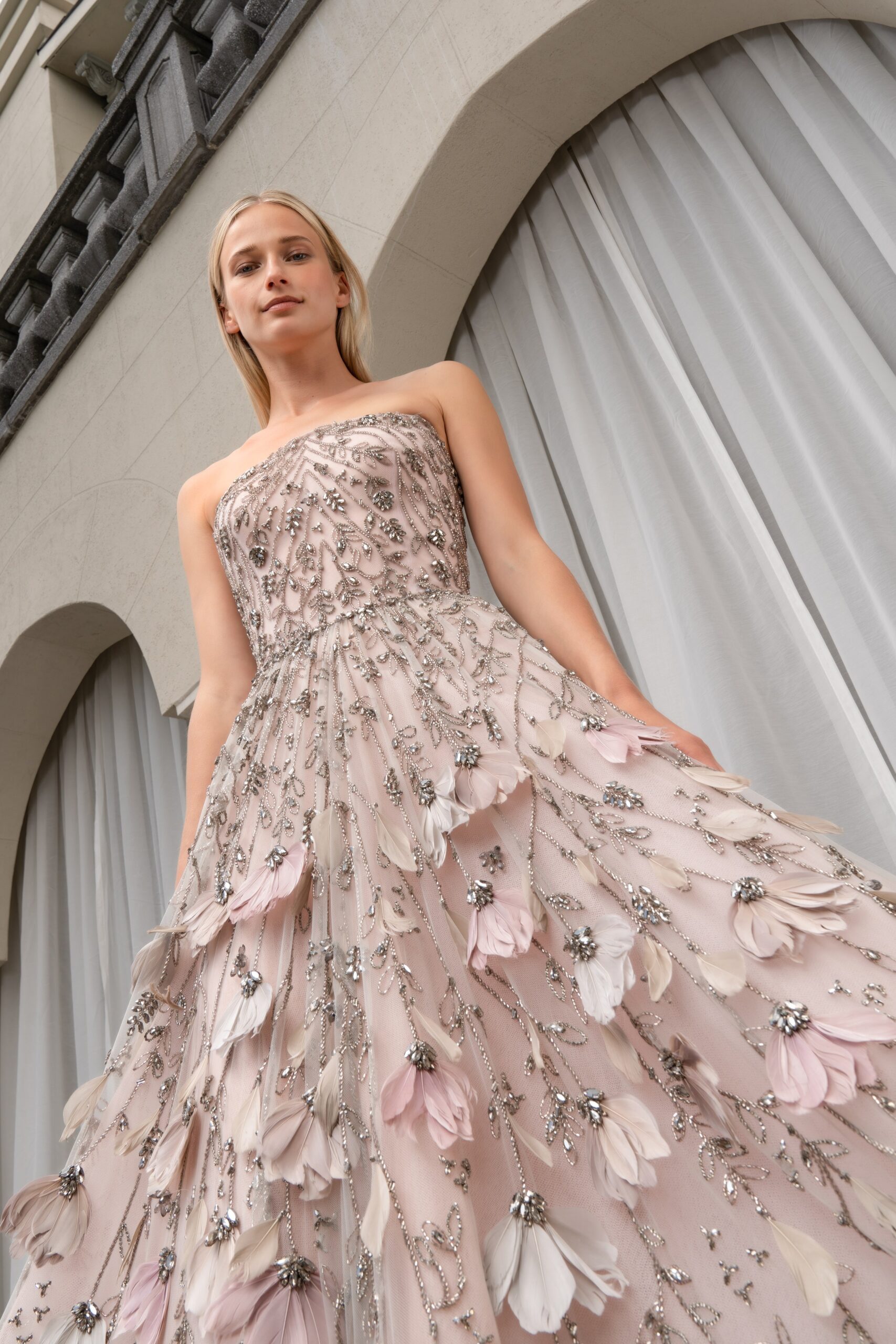 A fitted pink silk strapless gown with layered floral embroidery detailing.