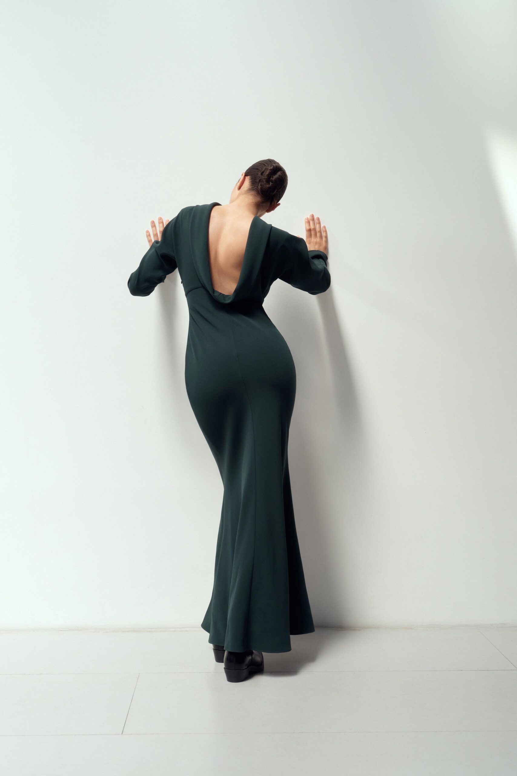 A fitted green long-sleeve gown with a deep V-neckline and a flowing maxi silhouette.