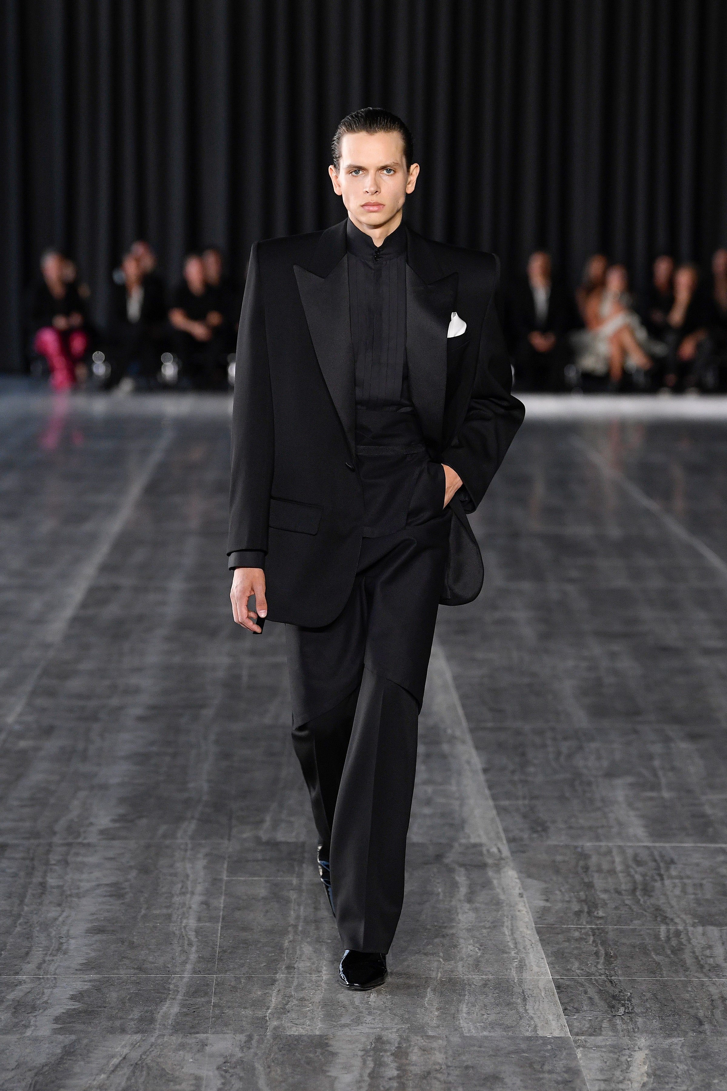 A tailored black wool suit with long sleeves and a collared shirt, featuring straight-leg trousers.