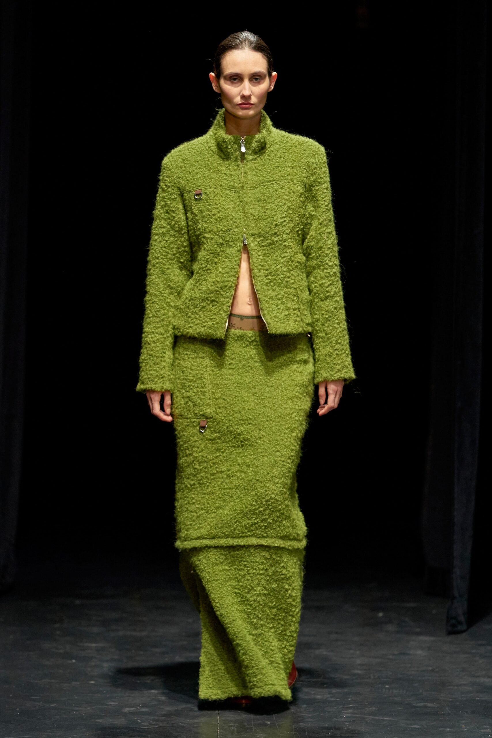 A fitted green wool jacket with long sleeves and an asymmetric skirt.