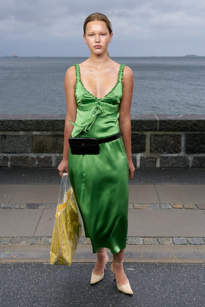 A fitted green silk dress with a V-neckline and a stylish slit detail.