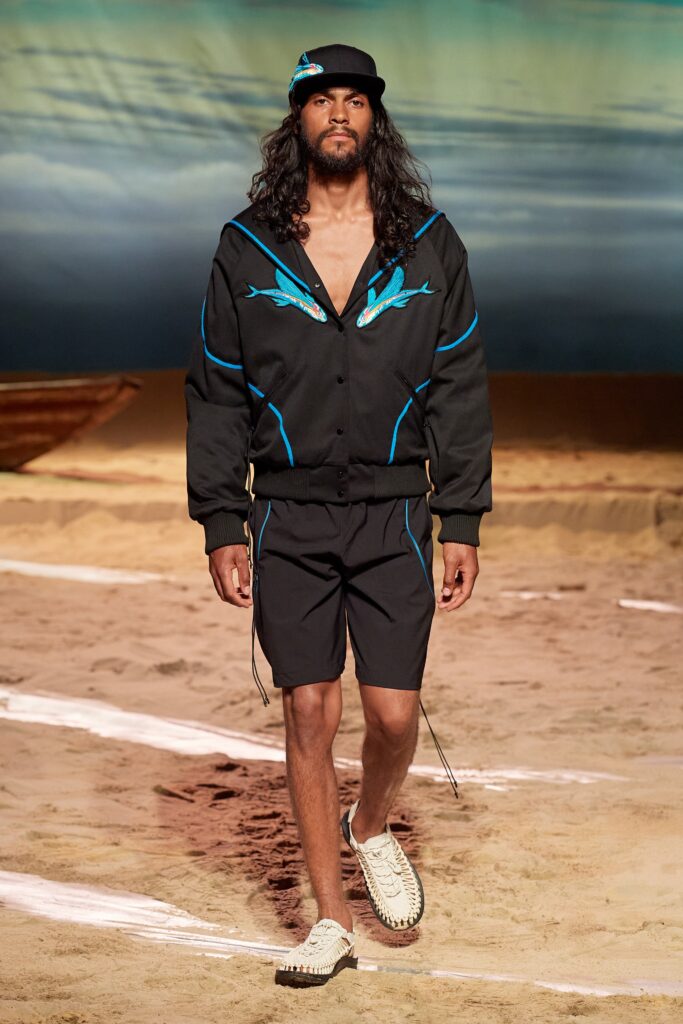 A relaxed black jacket with blue accents and matching shorts, featuring a zippered front and printed details.