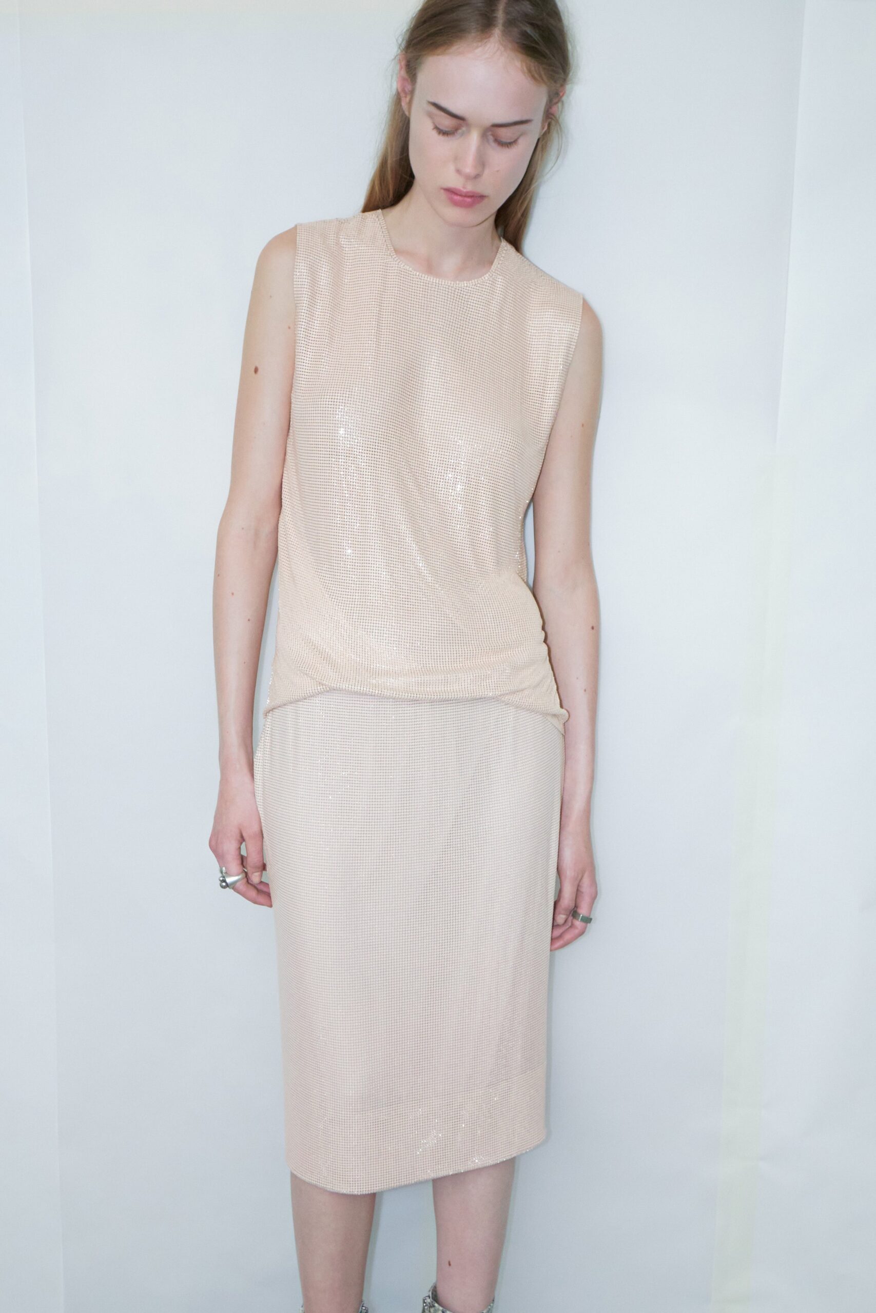 A fitted beige silk dress with a sleeveless design and straight-leg silhouette.
