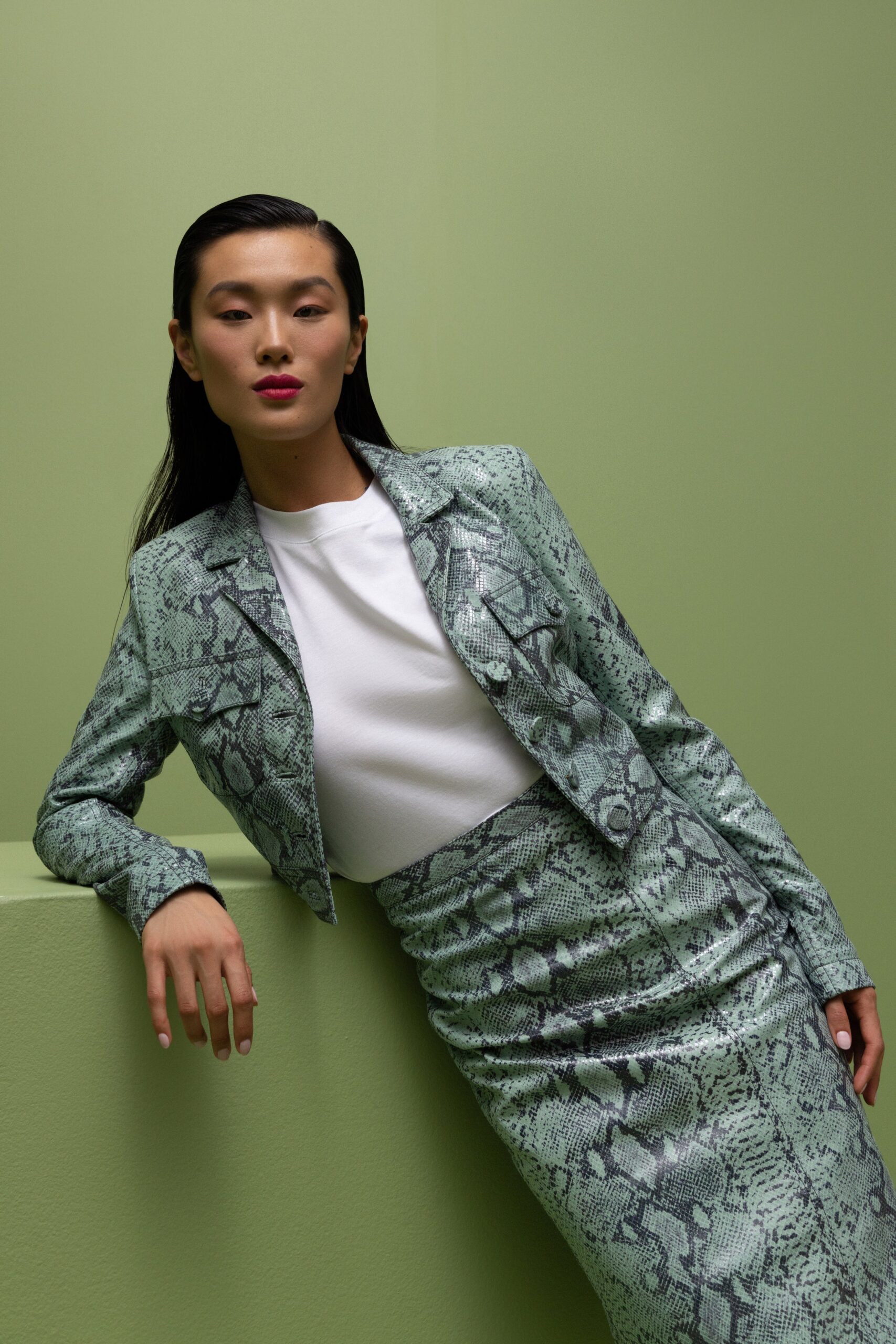 A fitted green printed blazer with a collared neckline paired with a matching skirt.