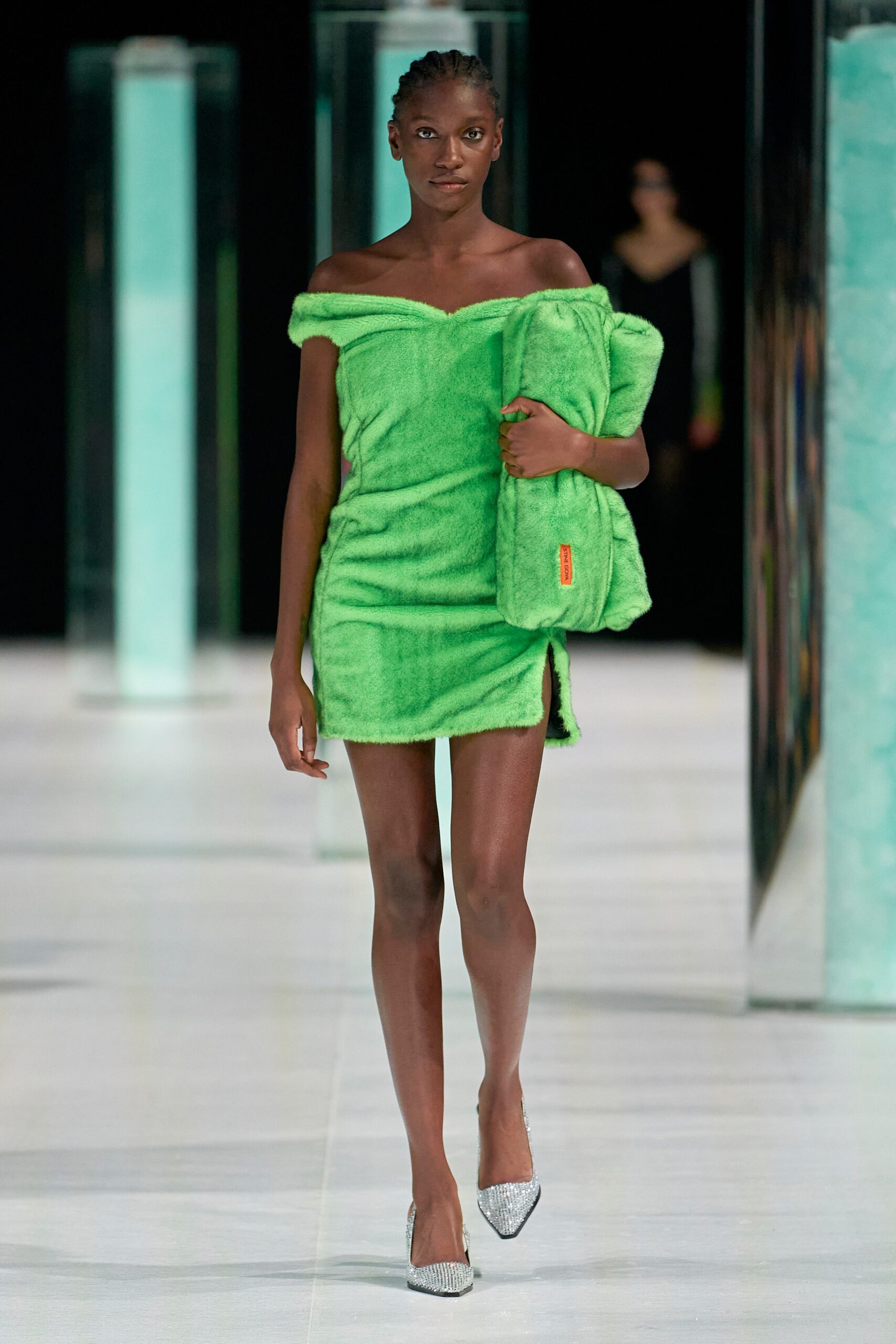 A fitted green faux-fur dress with an off-shoulder design and a mini silhouette featuring a side slit.