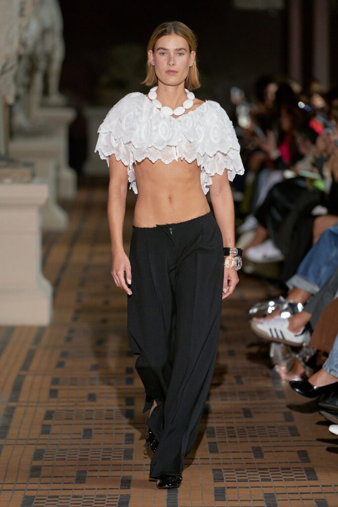 A relaxed white sleeveless cropped top paired with relaxed black pants.