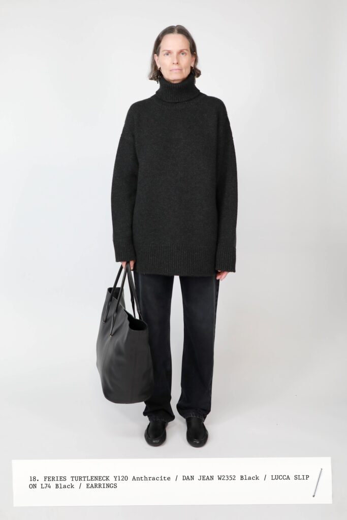 A relaxed black wool sweater with a turtleneck paired with straight-leg black pants.