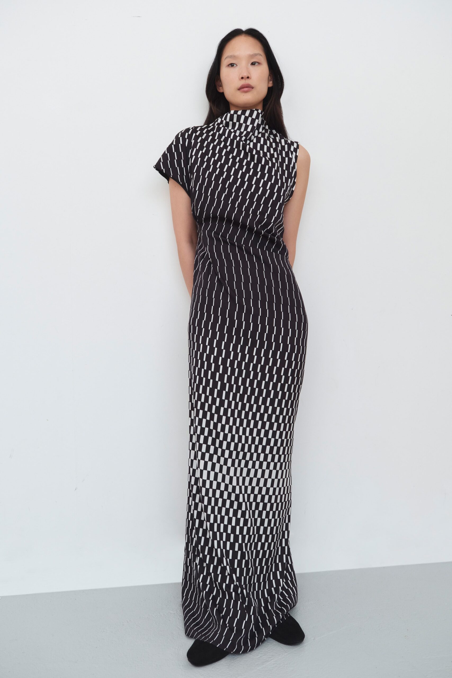 A fitted black and white printed dress with a high neckline and sleeveless design.
