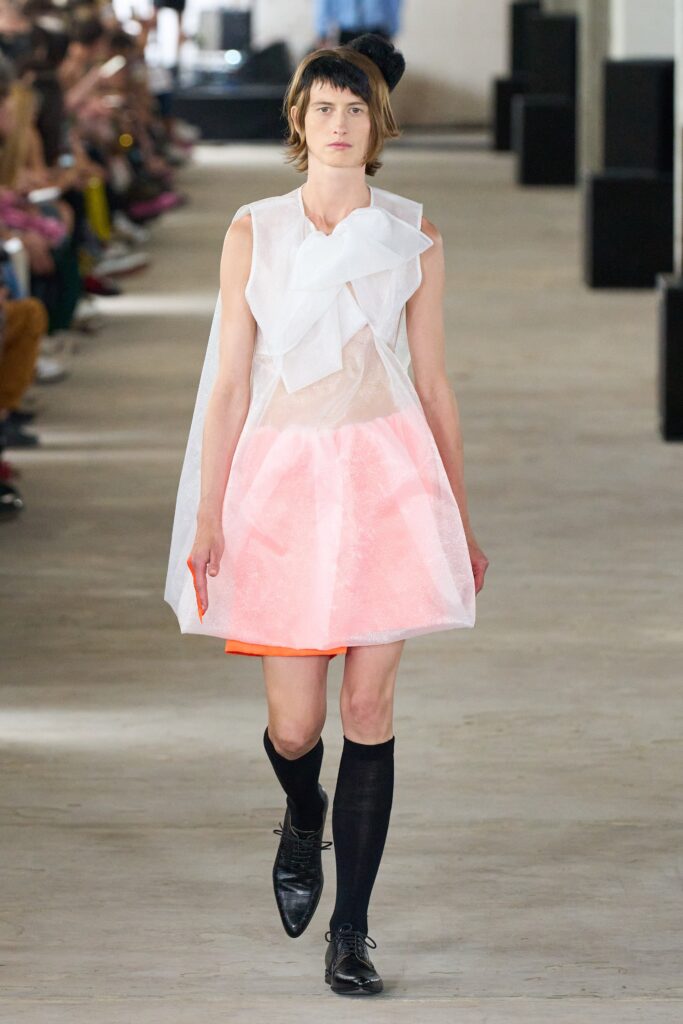 A fitted white and pink sleeveless dress with a V-neckline and asymmetric layered design.