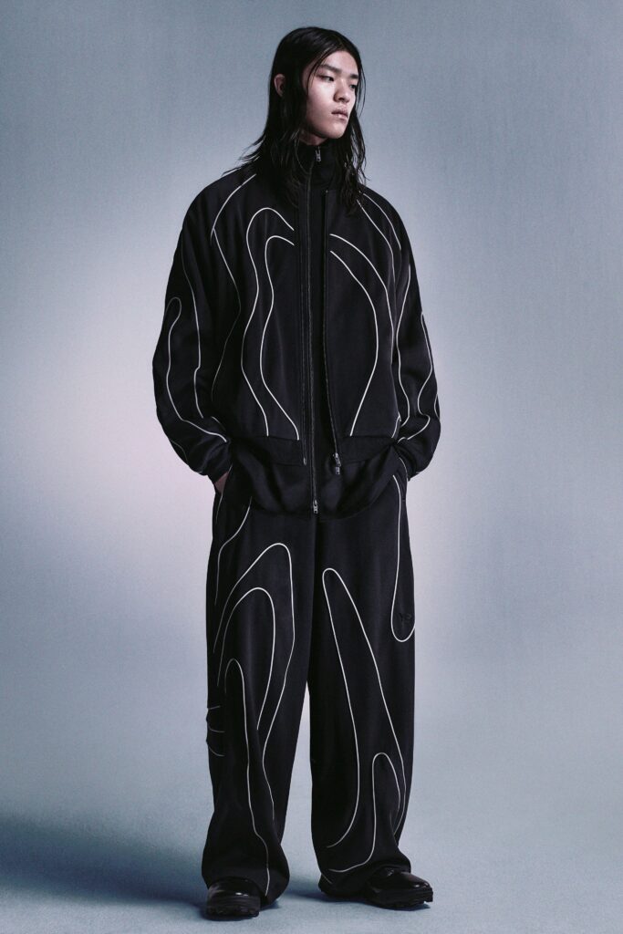A relaxed black jacket with long sleeves and asymmetric design paired with matching pants.