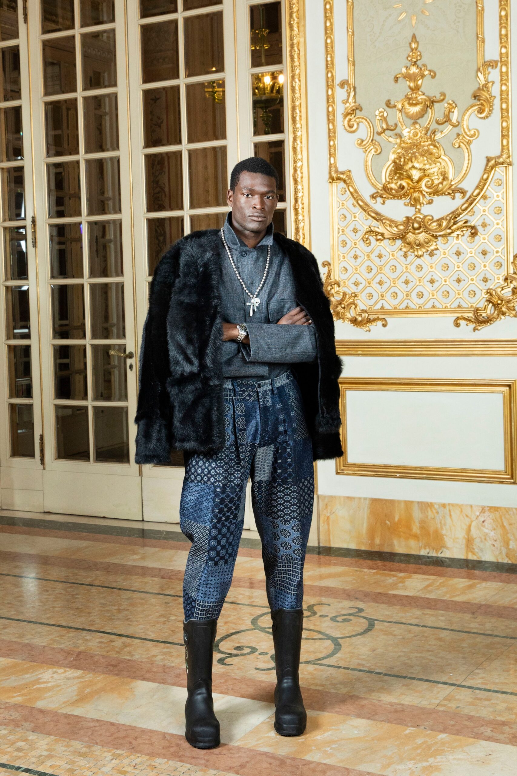 A fitted black fur coat paired with printed blue pants, showcasing a stylish runway look.