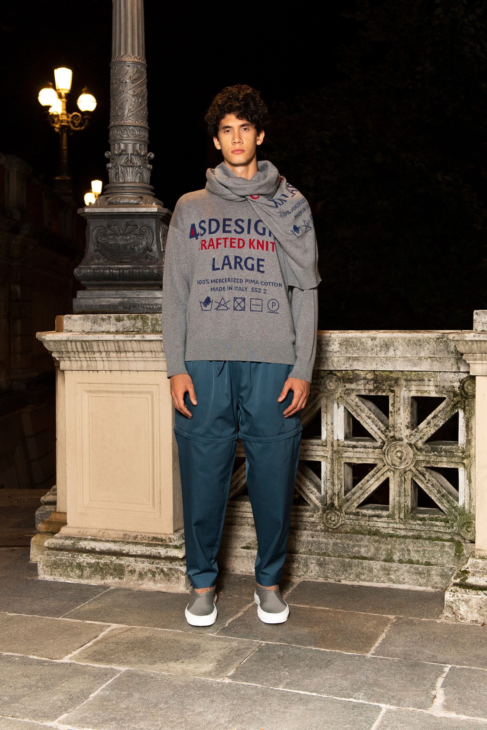 A relaxed gray long-sleeve sweater with a printed design, paired with blue relaxed-fit pants.