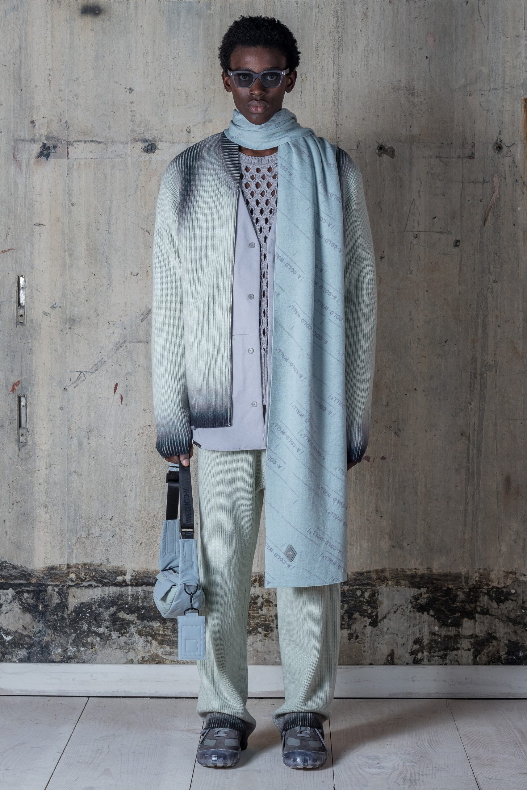 This relaxed long-sleeve sweater features a unique ombre effect, transitioning from a soft gray to a deeper tone, creating a visually striking gradient. Paired with matching pants, the ensemble emphasizes a contemporary silhouette, enhanced by layered textures that add depth and interest.
