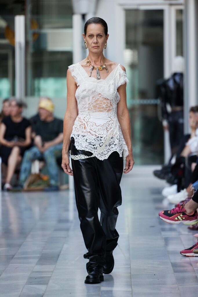 A sleeveless white lace top paired with loose-fitting black leather pants for a chic look.