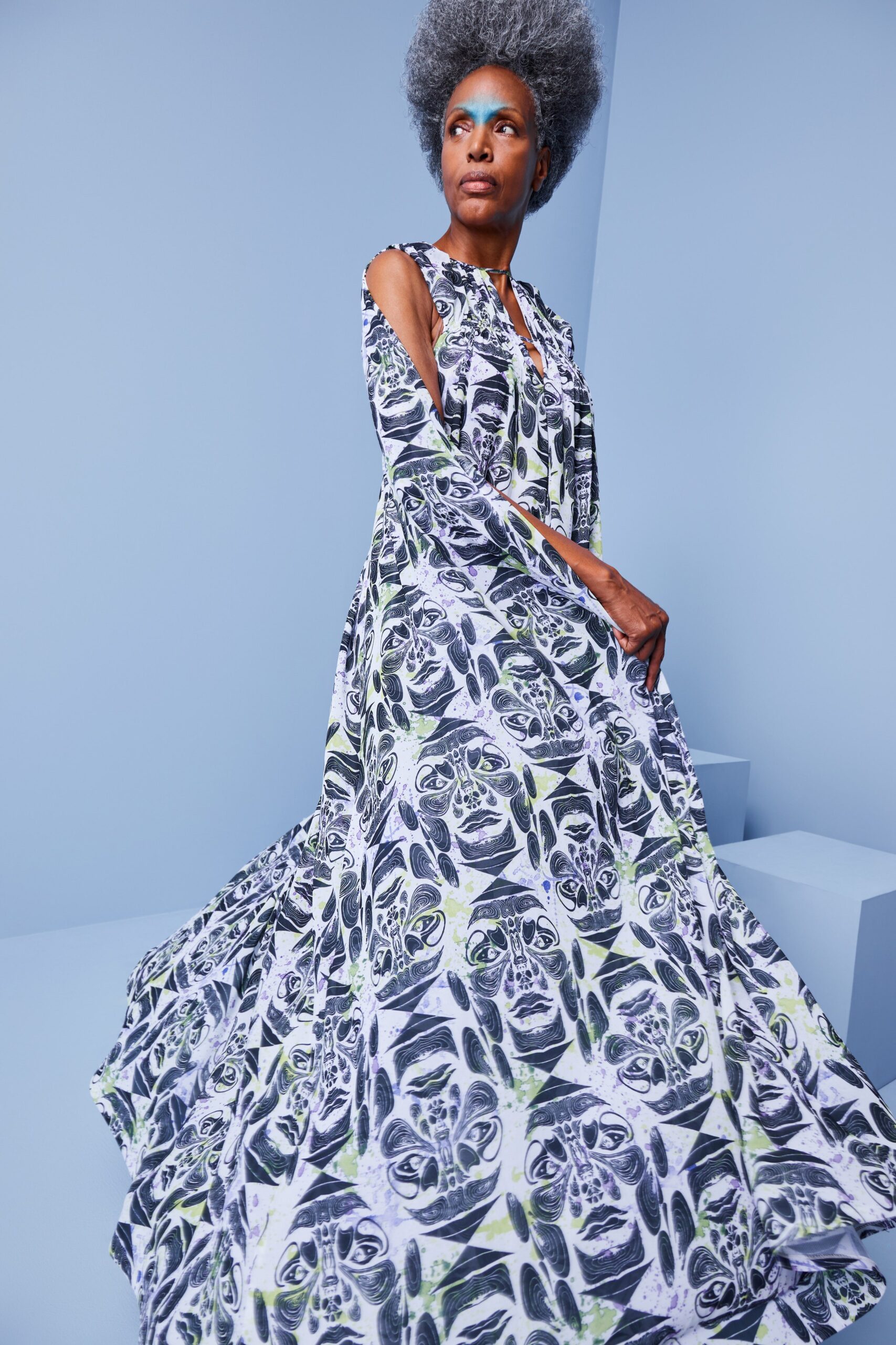 This relaxed dress features a vibrant, multi-colored print that captures attention with its artistic flair. The long sleeves and V-neckline enhance its flowing silhouette, while the tiered design adds depth and movement, creating a dynamic visual effect.