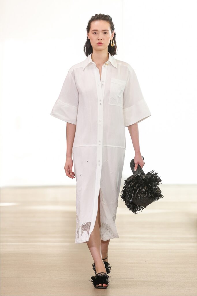A relaxed white cotton shirt-dress with short sleeves and a buttoned front featuring a slit.