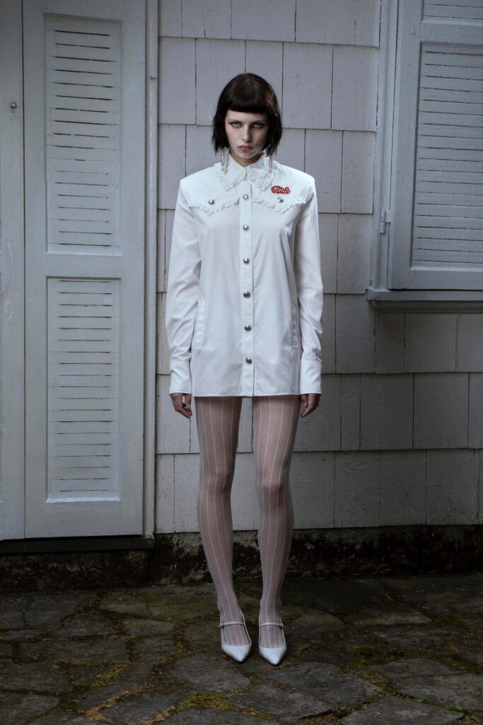 A fitted white cotton shirt-dress with long sleeves and a collared neckline, featuring button details.