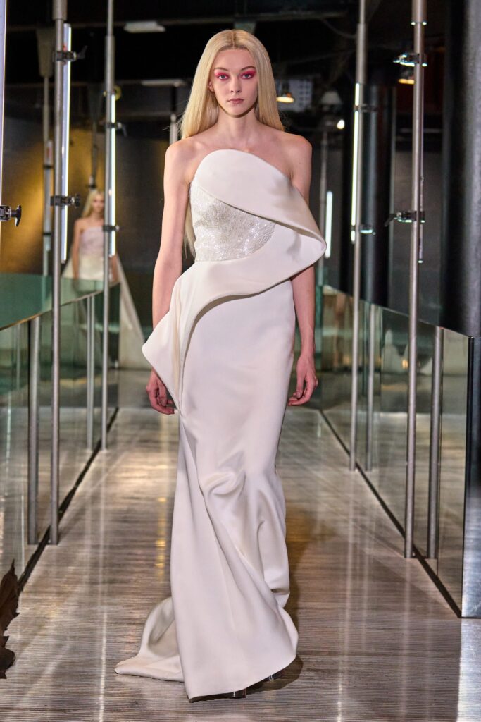 A fitted white silk strapless gown with a draped design detail.