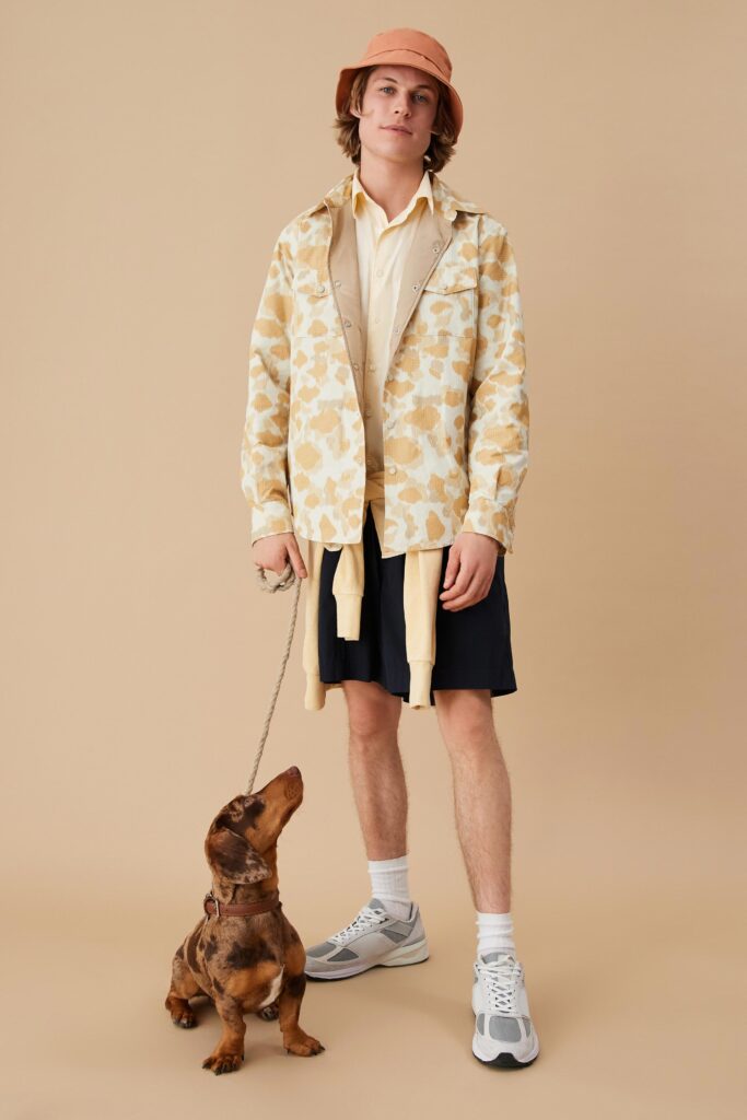 A relaxed-fit beige printed jacket over a collared shirt paired with black shorts.
