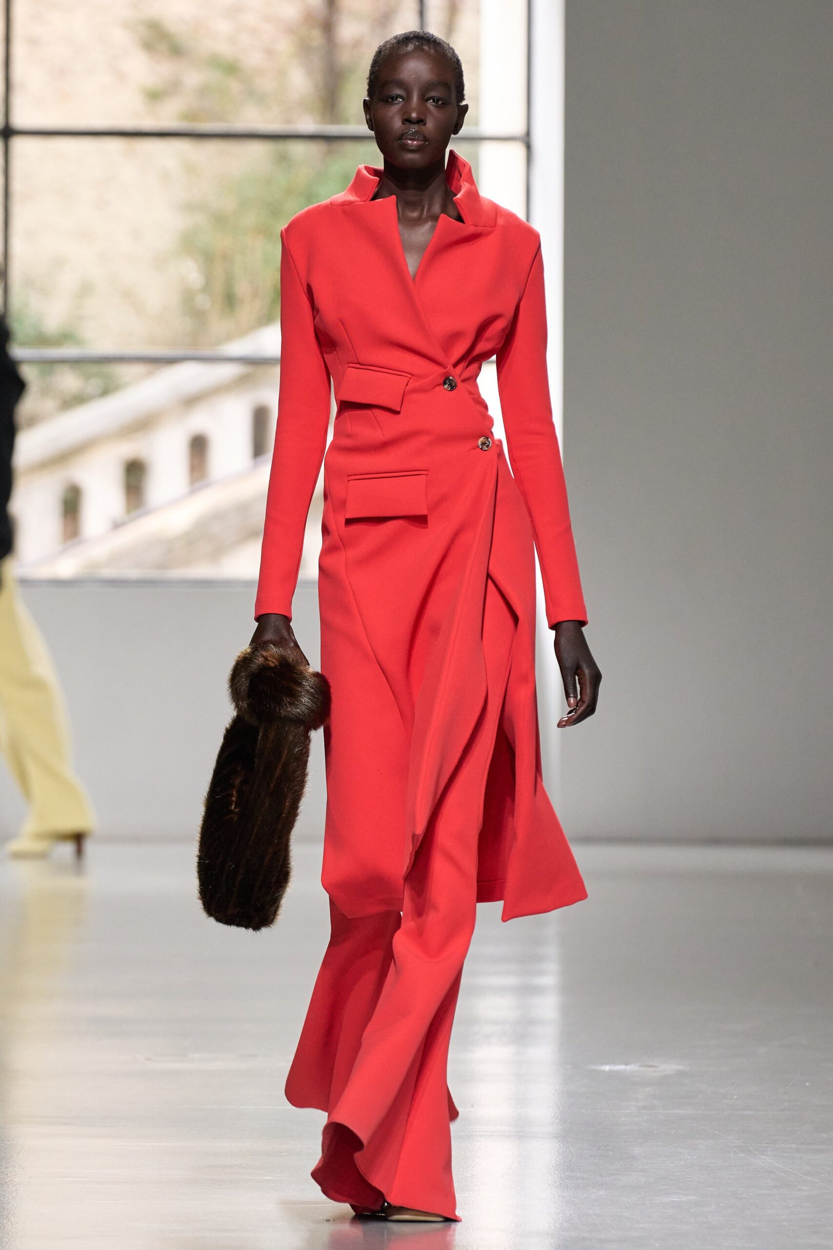 A fitted red wool dress with long sleeves, a collared neckline, and an asymmetric belted design.