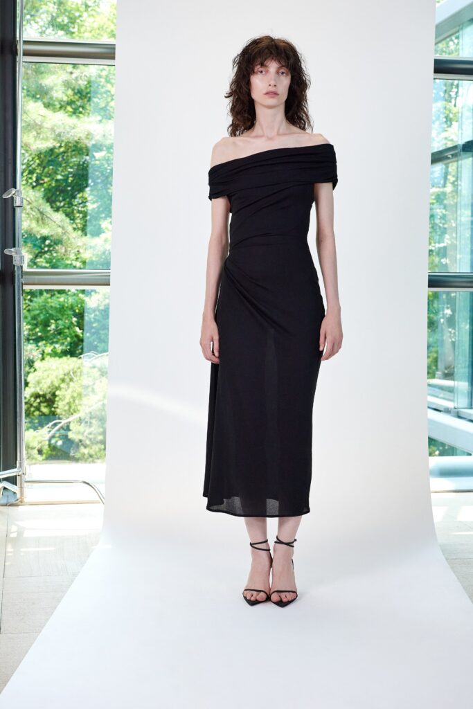 A fitted black silk off-shoulder dress featuring a draped design for an elegant look.