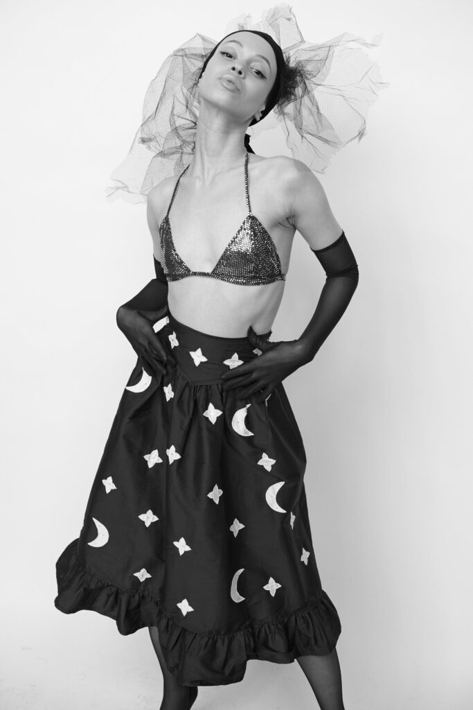 A fitted black pleated skirt paired with a sleeveless sequined top, creating a striking silhouette.