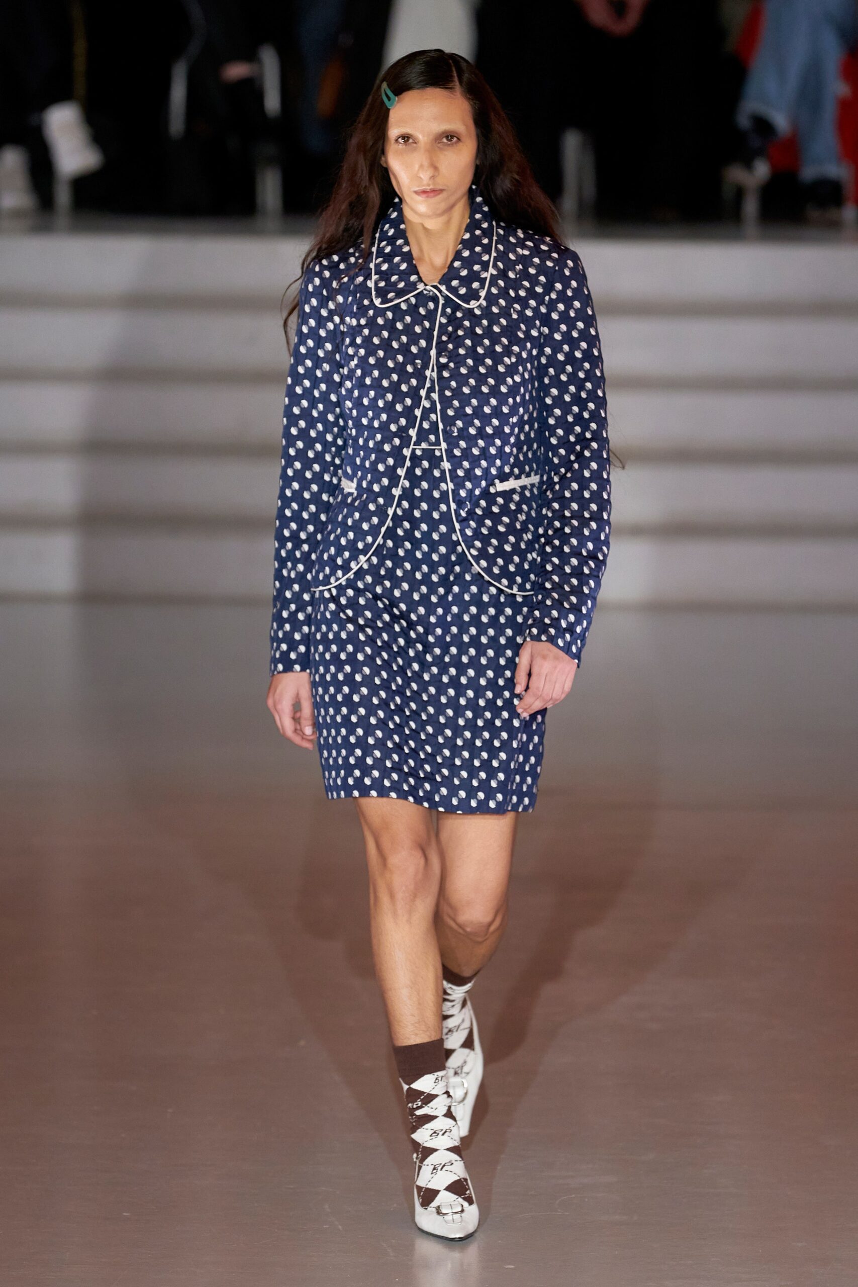 A fitted blue dress with long sleeves, a collared neckline, and a printed design.