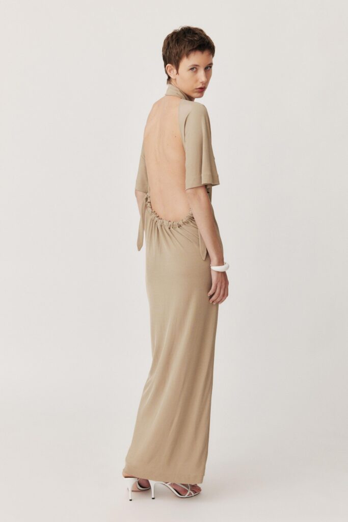 A fitted beige silk dress with a backless design and maxi length.