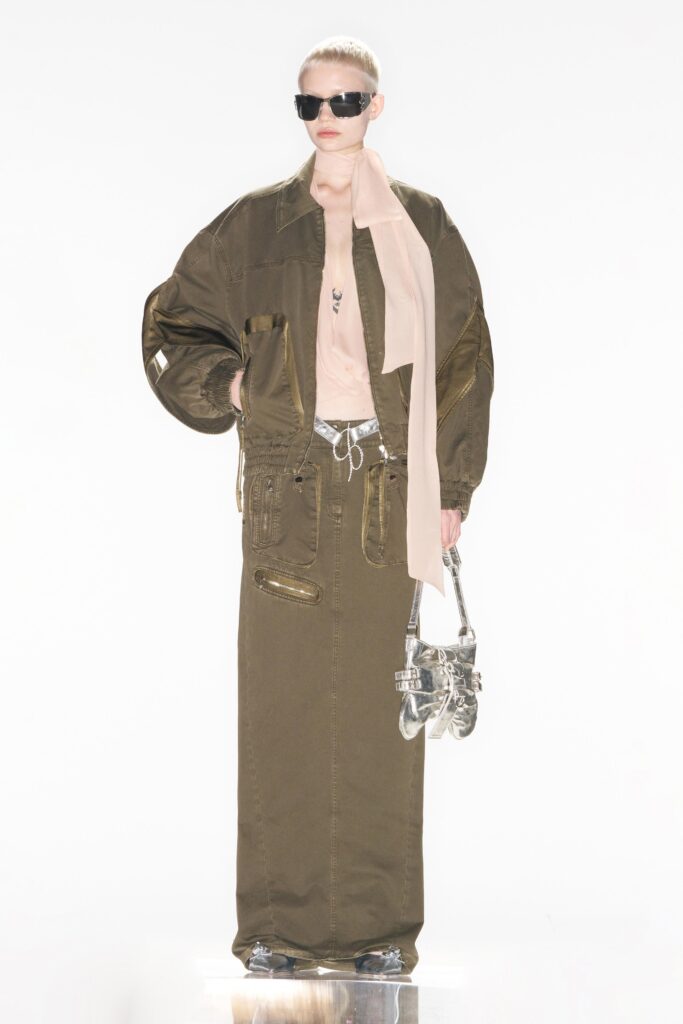 A relaxed green denim jacket with long sleeves paired with a zippered straight-leg skirt.