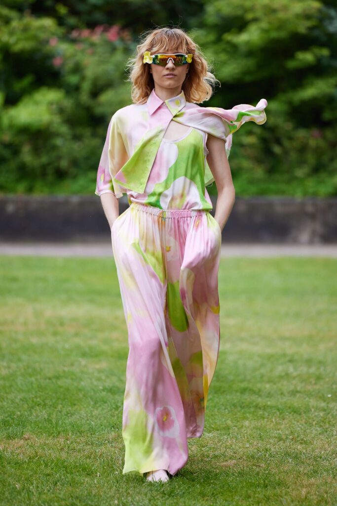 An asymmetric long-sleeve silk top paired with flowy pink and green pants.