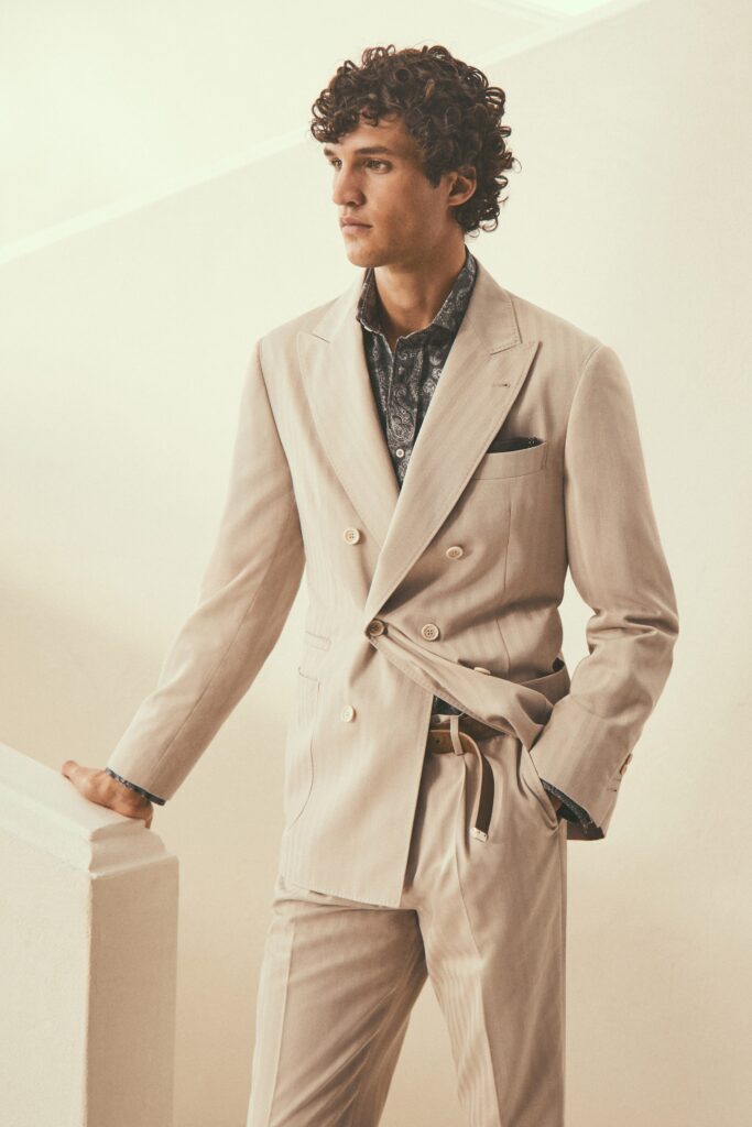 A tailored beige suit with a long-sleeve collared shirt and buttoned details.