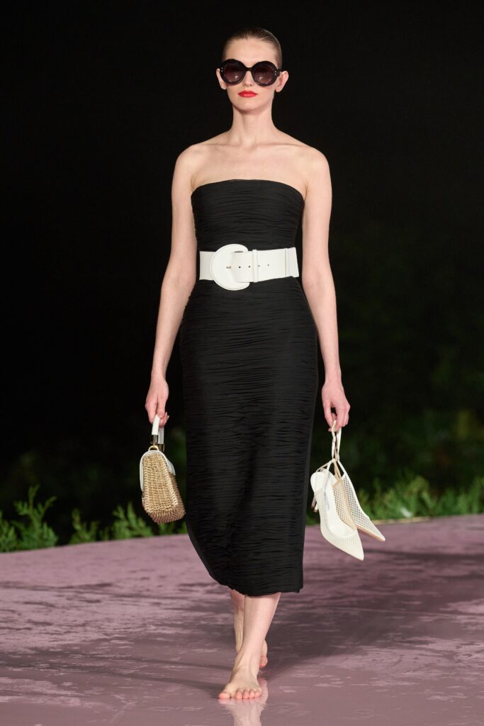 A fitted black strapless dress with a pleated design and a high neckline.